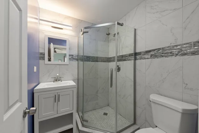 a bathroom with a shower sink mirror and toilet