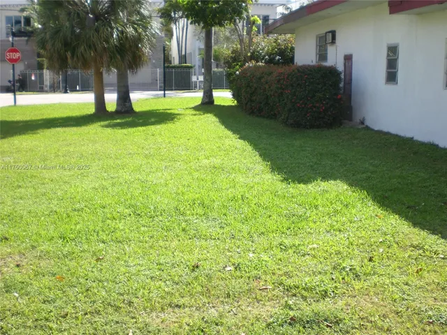 a backyard of a house with plants and palm tree