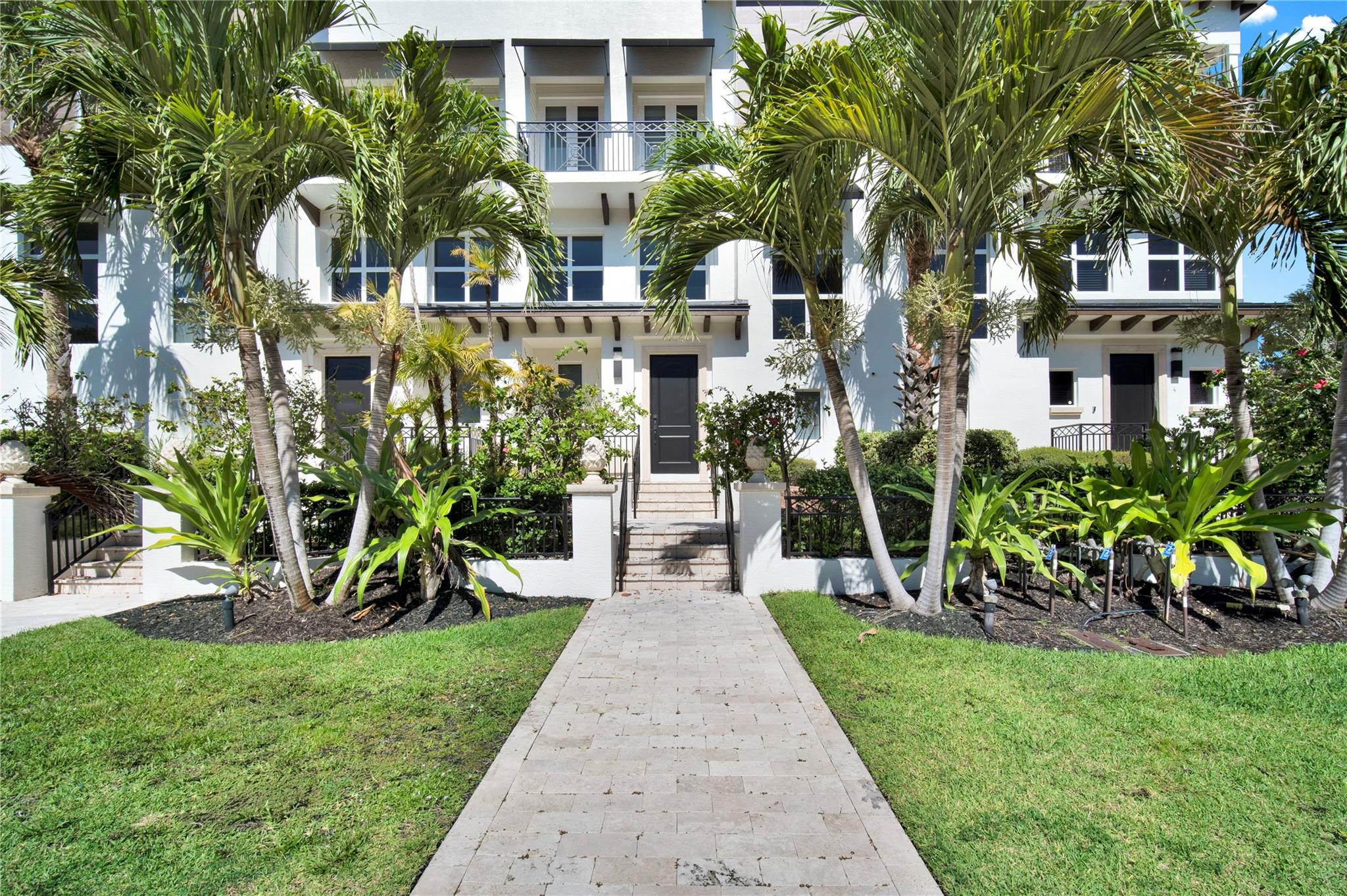 a front view of a house with a small yard and potted plants