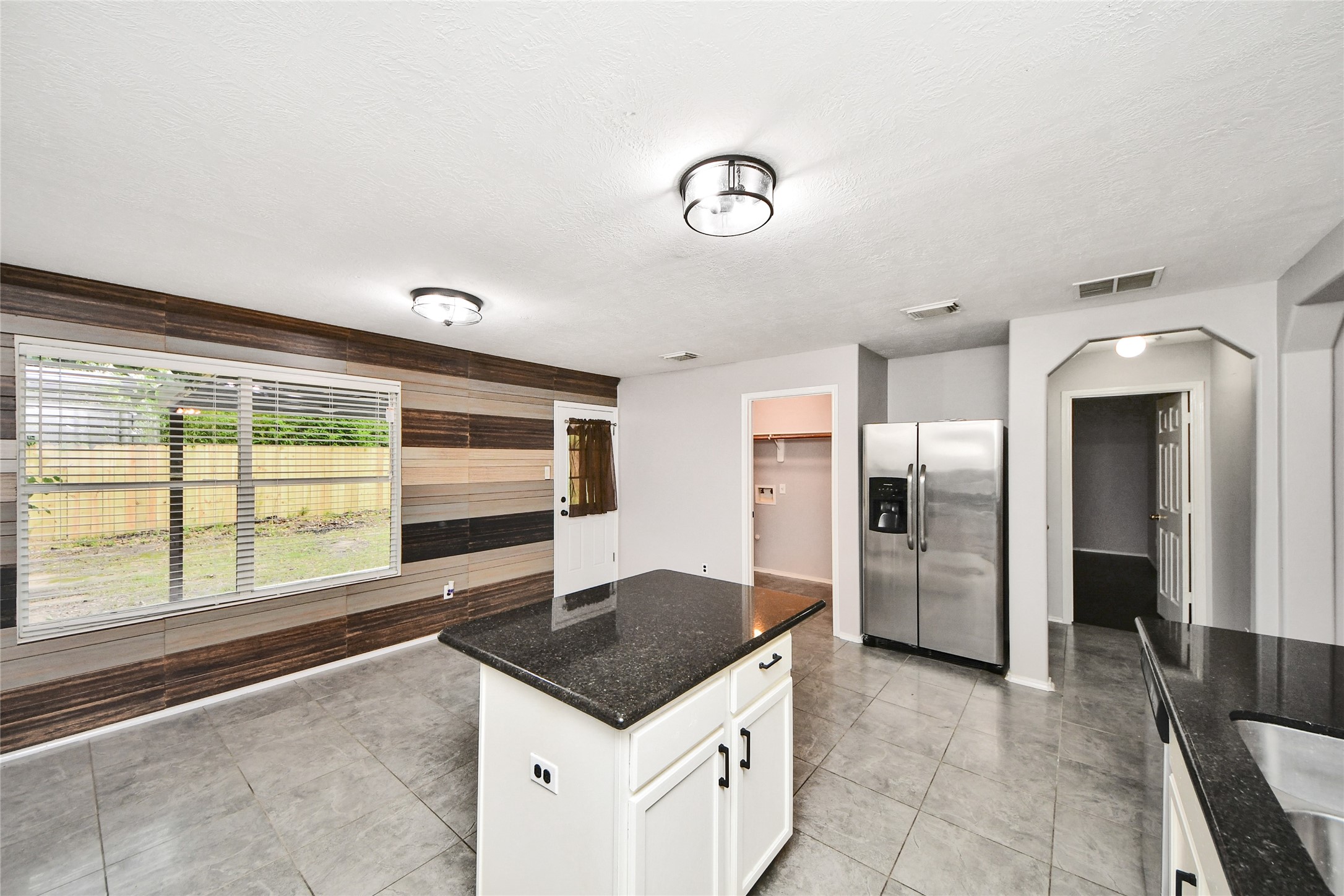 24019 Kingbriar Drive Spring, TX 77373 - Photo 17 of 41 The kitchen transitions beautifully into a versatile dining or breakfast area, featuring a striking wood-plank accent wall that adds warmth and character to the space.