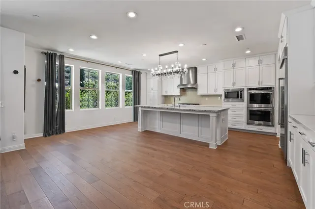 a large kitchen with stainless steel appliances granite countertop a large counter top and a wooden floors