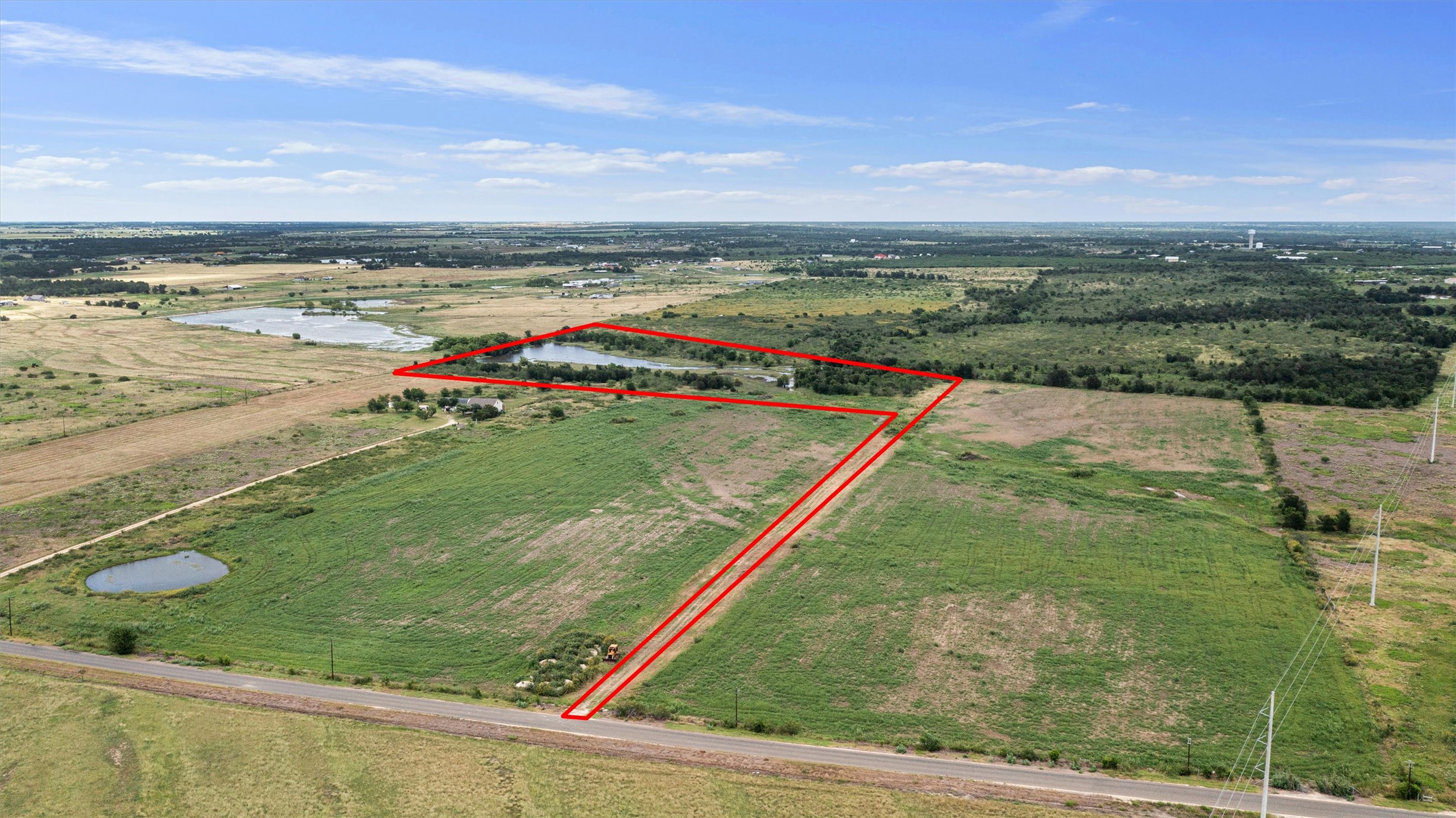 3315 County Road 463 Elgin, TX 78621 - Photo 8 of 32 An aerial perspective reveals a vast expanse of verdant land bordering a tranquil pond, perfect for rural living.