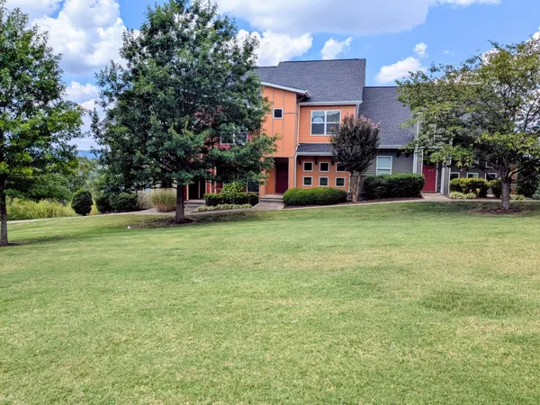a view of a house with a big yard and large trees