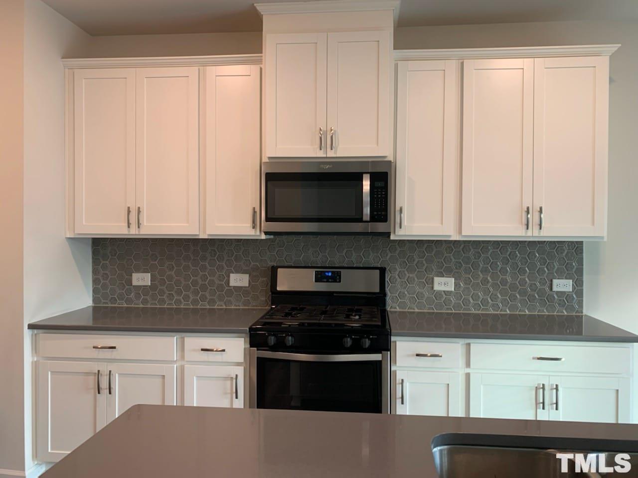 3413 Dropseed Drive Apex, NC 27502 - Photo 11 of 23 a kitchen with granite countertop white cabinets and black appliances
