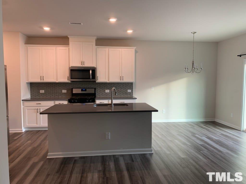 3413 Dropseed Drive Apex, NC 27502 - Photo 8 of 23 a kitchen with stainless steel appliances granite countertop a stove a sink and a refrigerator