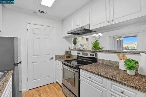 a kitchen with stainless steel appliances granite countertop white cabinets and a stove