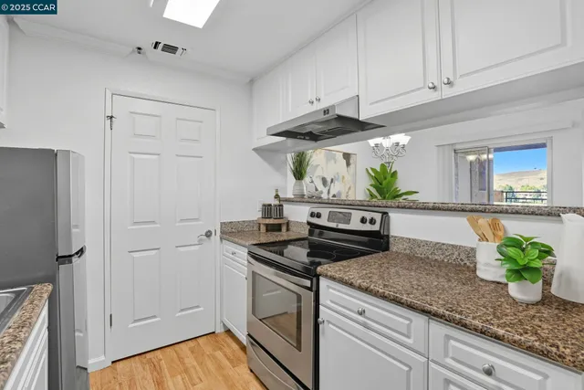 a kitchen with stainless steel appliances granite countertop white cabinets and a stove