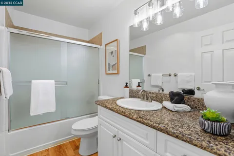 a bathroom with a granite countertop sink a toilet and a mirror