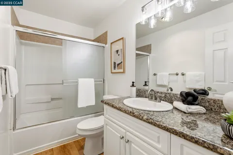 a bathroom with a granite countertop sink toilet and shower