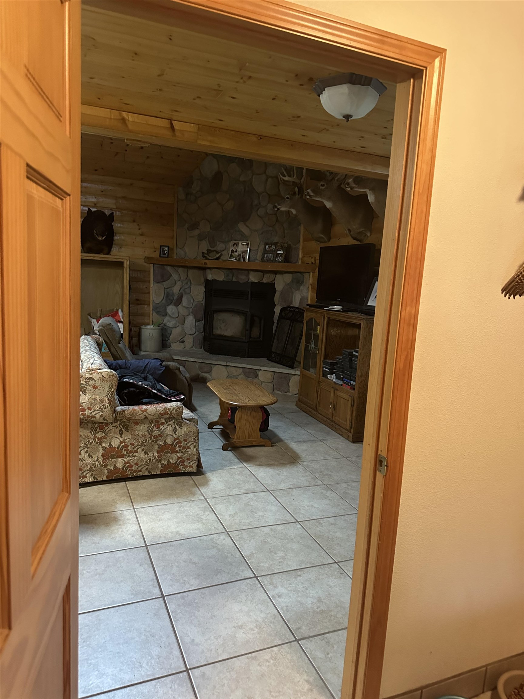 58875 Roy Anderson Road Mason, WI 54856 - Photo 19 of 26 Living room with light tile patterned flooring, lofted ceiling, and a stone fireplace