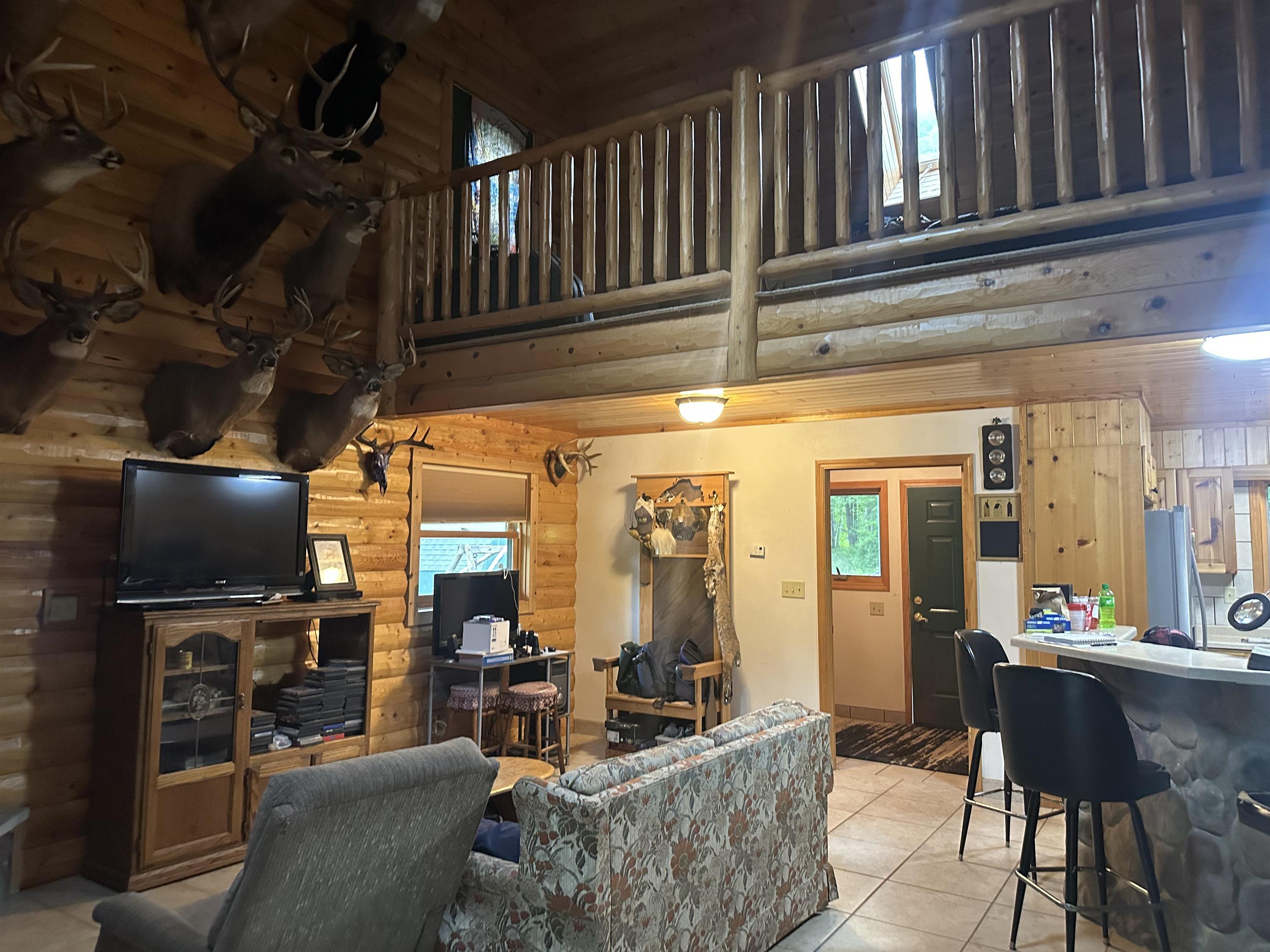 58875 Roy Anderson Road Mason, WI 54856 - Photo 5 of 26 Living room featuring tile patterned floors, log walls, and a towering ceiling