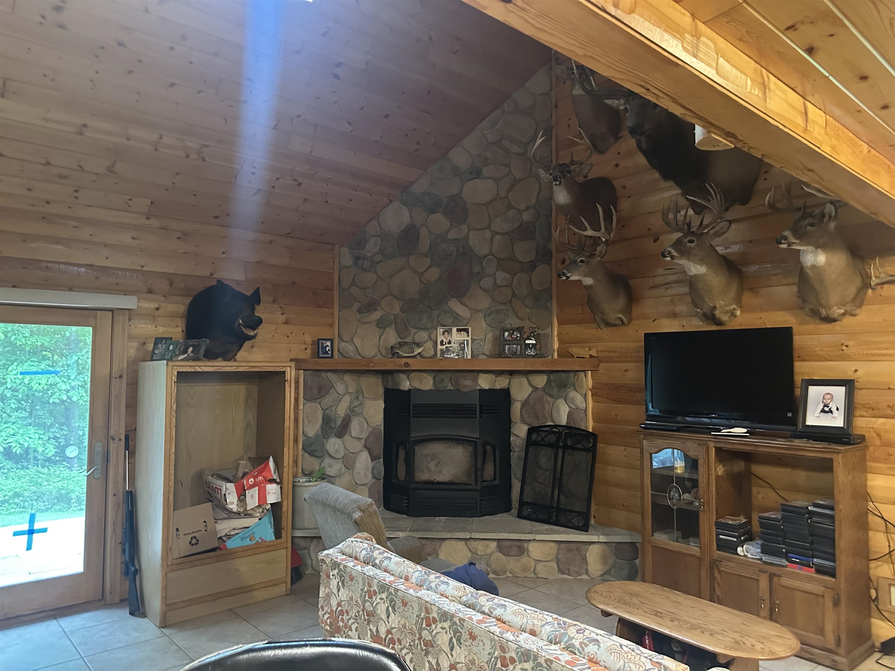 58875 Roy Anderson Road Mason, WI 54856 - Photo 7 of 26 Living room with light tile patterned flooring, a wood stove, vaulted ceiling, and wooden walls