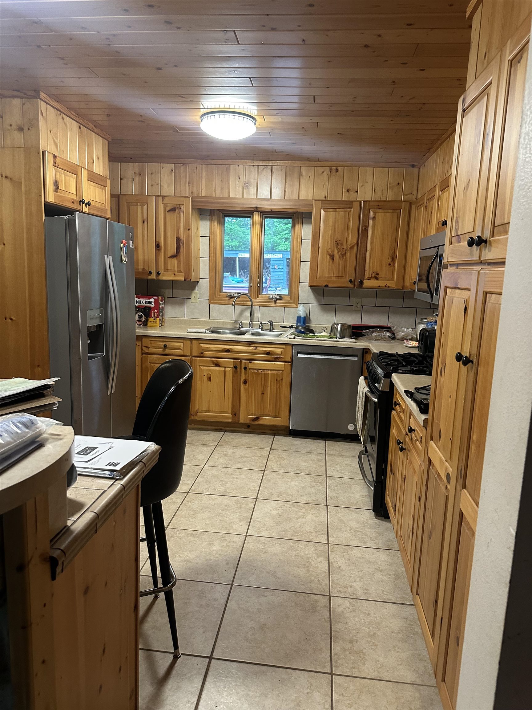 58875 Roy Anderson Road Mason, WI 54856 - Photo 9 of 26 Kitchen with appliances with stainless steel finishes, a sink, wood ceiling, light countertops, and light tile patterned floors