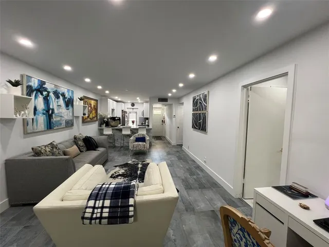 a living room with couches and kitchen view with wooden floor
