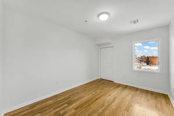 a view of empty room with wooden floor and fan