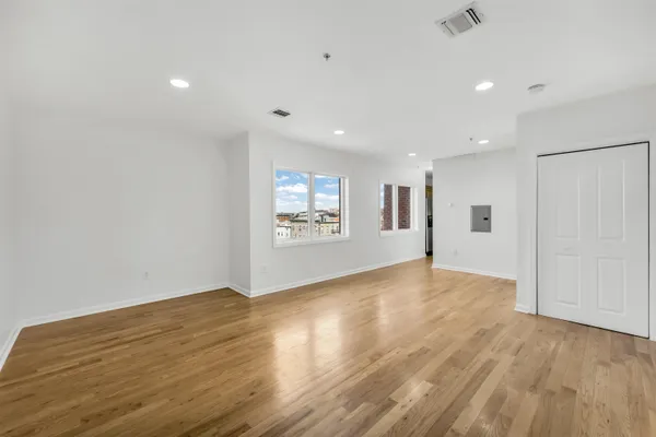 an empty room with wooden floor and windows
