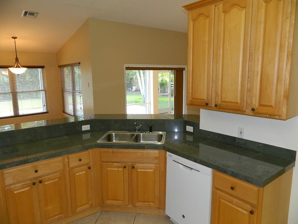 5702 Southeast Hull Street Stuart, FL 34997 - Photo 8 of 12 a kitchen with granite countertop white cabinets and sink
