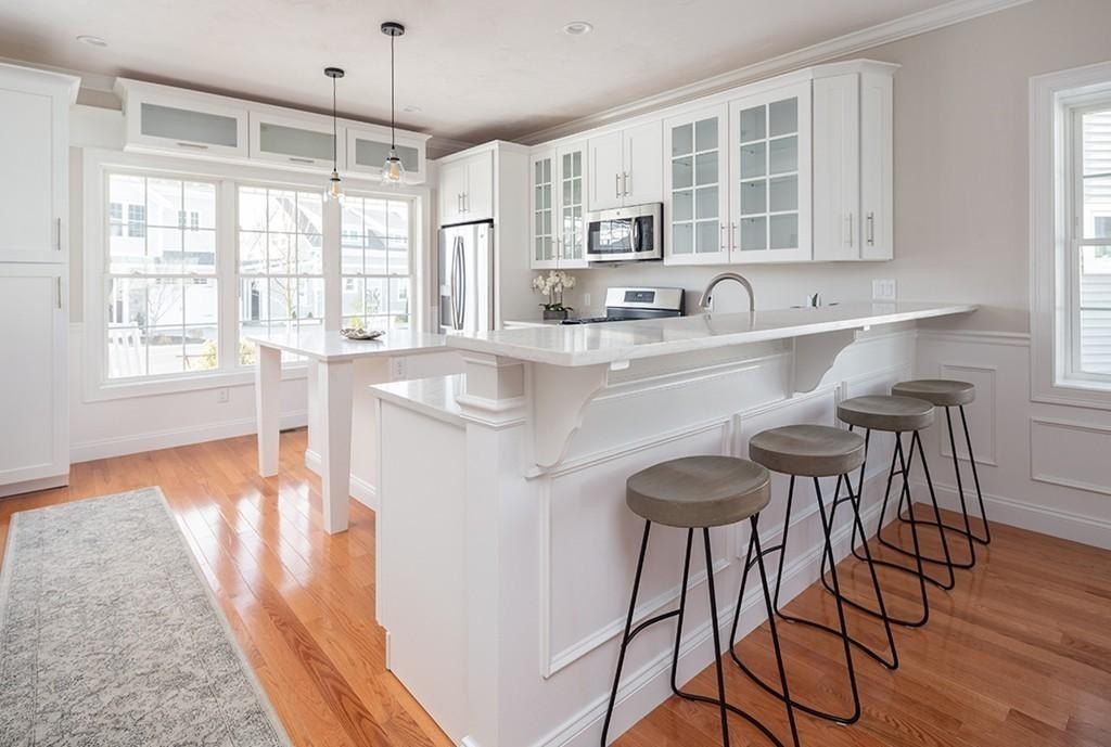 135 Sumner Street, Unit 1 Quincy, MA 02169 - Photo 5 of 13 a kitchen with stainless steel appliances granite countertop a stove top oven a sink a dining table and chairs with wooden floor