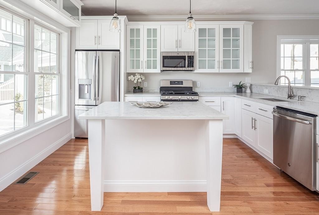 135 Sumner Street, Unit 1 Quincy, MA 02169 - Photo 6 of 13 a kitchen with stainless steel appliances granite countertop a stove a sink a refrigerator a microwave and cabinets