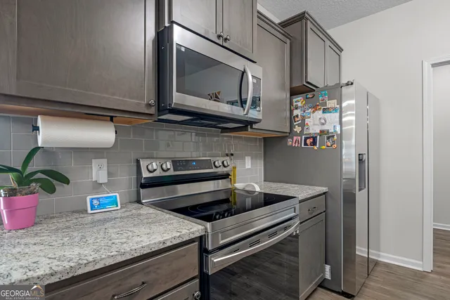 a kitchen with stainless steel appliances kitchen island granite countertop a sink dishwasher a refrigerator and a stove with wooden floor