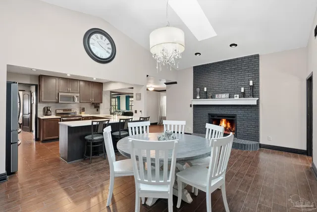 a view of a dining room and livingroom with furniture wooden floor a rug and a clock