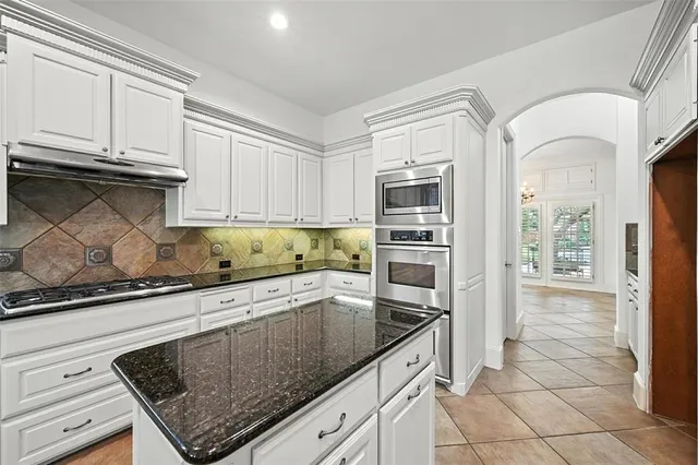 a kitchen with granite countertop a stove a sink and a refrigerator