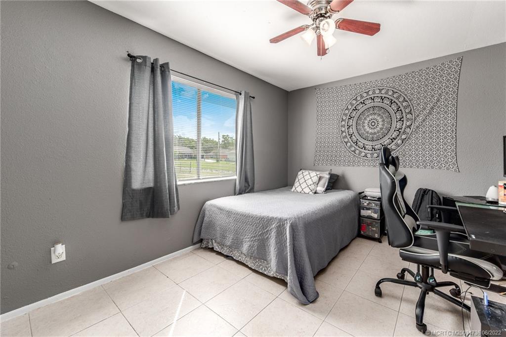 255 Southwest Homeland Road Port St. Lucie, FL 34953 - Photo 12 of 15 a bedroom with a bed and a chandelier