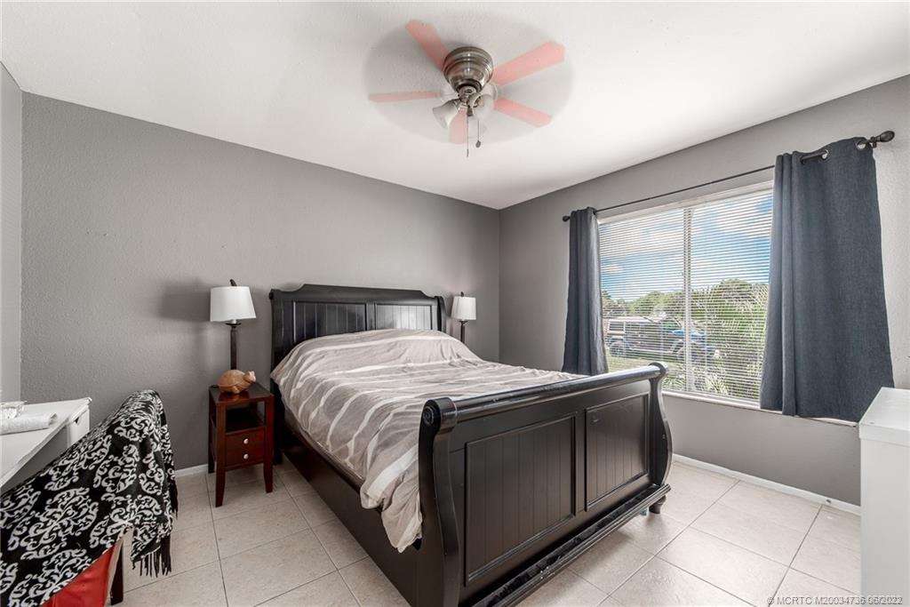 255 Southwest Homeland Road Port St. Lucie, FL 34953 - Photo 10 of 15 a bedroom with a bed and a chandelier