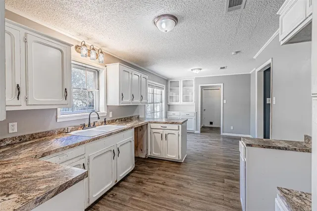 a kitchen with a sink dishwasher a stove and white cabinets with wooden floor