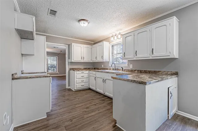 a kitchen with stainless steel appliances granite countertop a stove a refrigerator and white cabinets with wooden floor