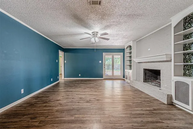 a view of an empty room with a fireplace and a window