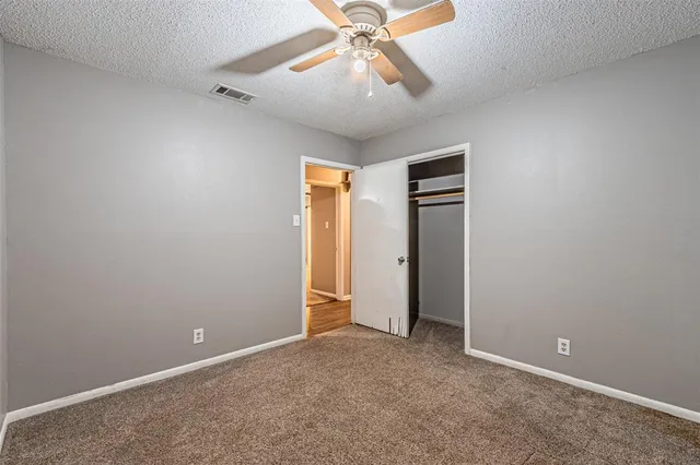 an empty room with closet and a chandelier fan
