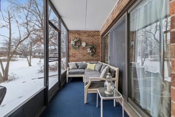 a balcony with couple of chairs and a wooden bench