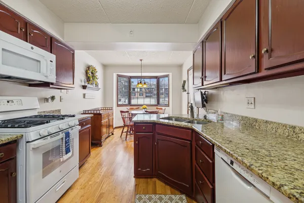 a kitchen with stainless steel appliances granite countertop wooden cabinets a sink dishwasher a stove and a refrigerator