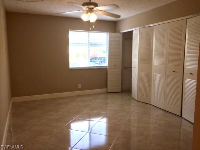 3655 Boca Ciega Drive, Unit 102 Naples, FL 34112 - Photo 11 of 27 en empty room with windows and chandelier fan
