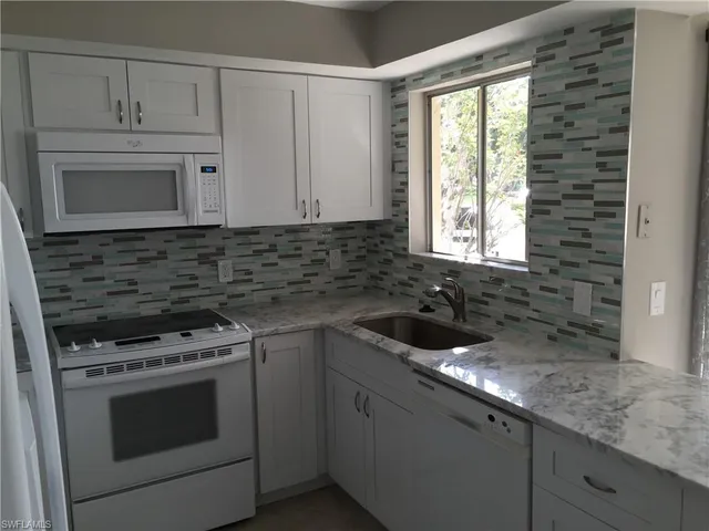a kitchen with granite countertop white cabinets and appliances