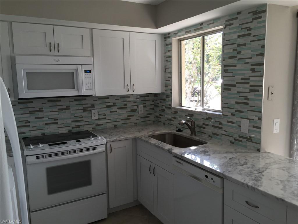 3655 Boca Ciega Drive, Unit 102 Naples, FL 34112 - Photo 3 of 27 a kitchen with granite countertop white cabinets and appliances