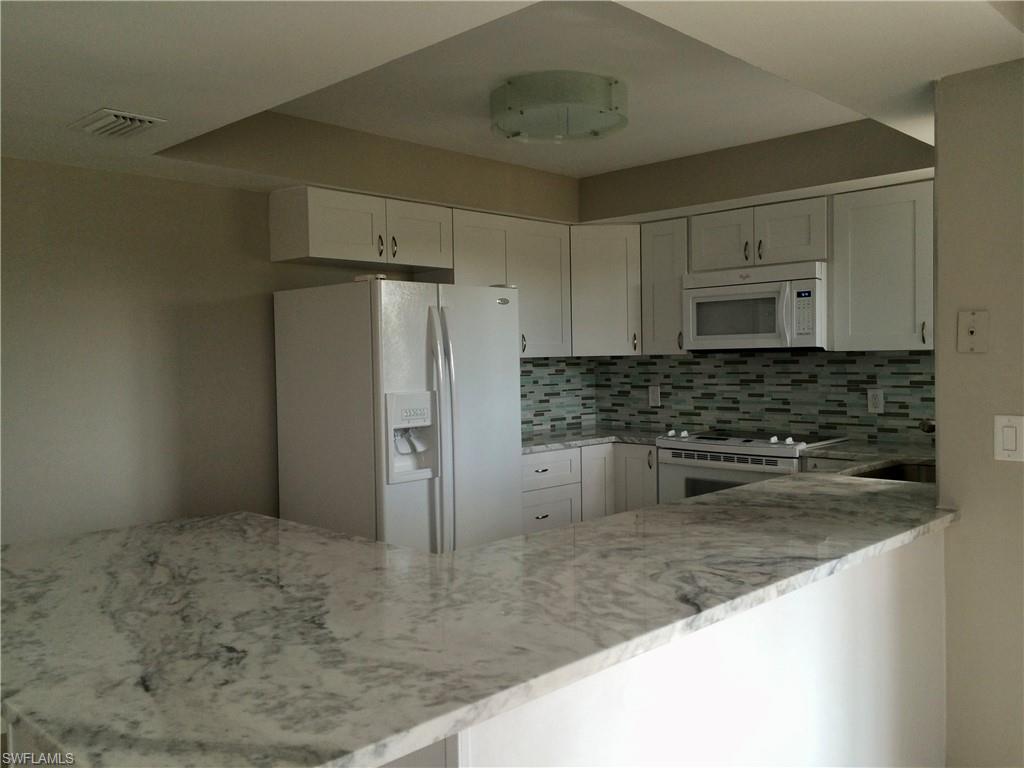 3655 Boca Ciega Drive, Unit 102 Naples, FL 34112 - Photo 7 of 27 a kitchen with stainless steel appliances granite countertop a sink a refrigerator and a granite counter tops