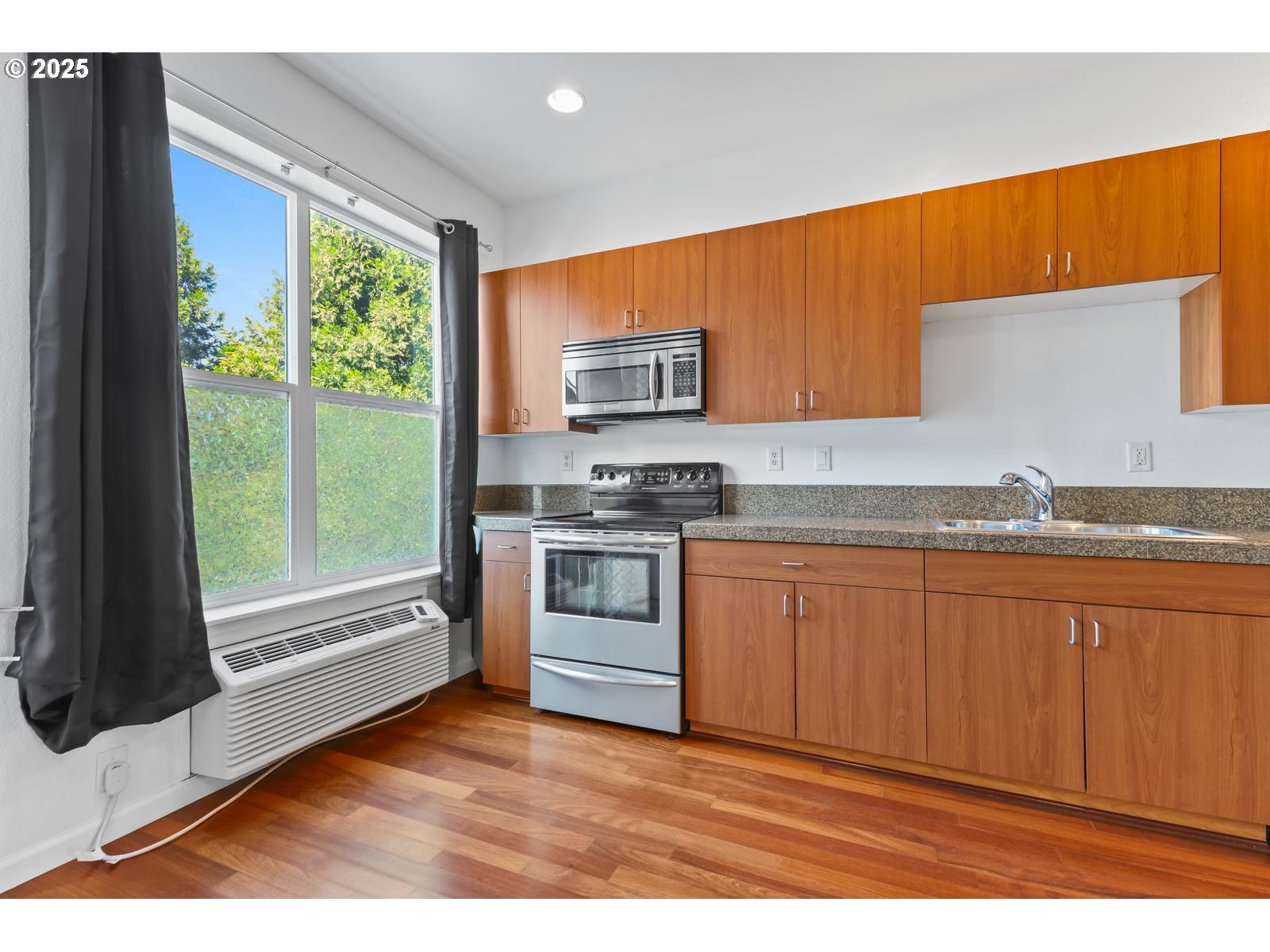 8712 North Decatur Street, Unit 105 Portland, OR 97203 - Photo 25 of 38 a kitchen with granite countertop wooden cabinets a stove a sink and a large window