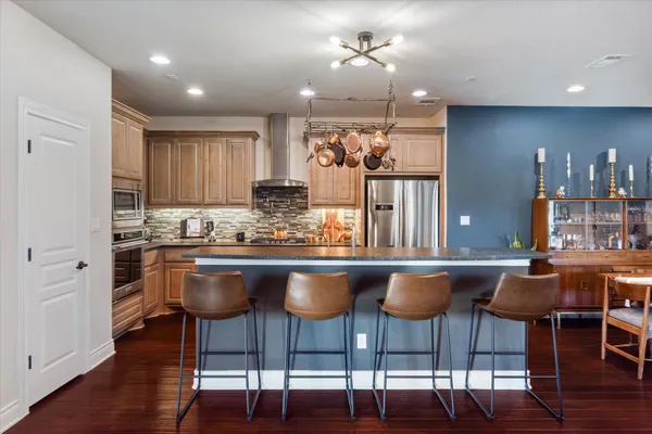 a kitchen with granite countertop a dining table chairs cabinets wooden floor and appliances