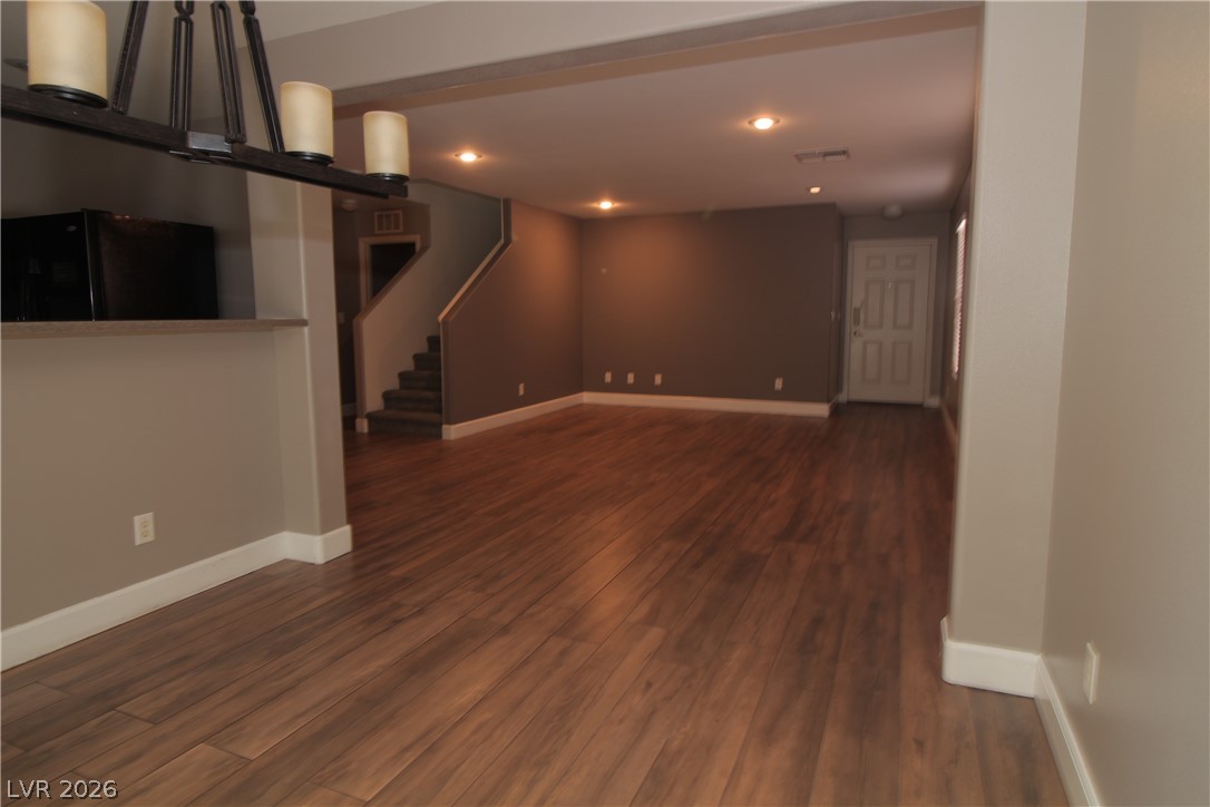 9289 Valley Ranch Avenue Las Vegas, NV 89178 - Photo 7 of 29 Rich wood flooring extends through this open-concept space, leading to a modern staircase.