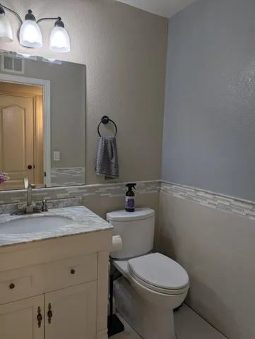 a bathroom with a granite countertop toilet sink and mirror