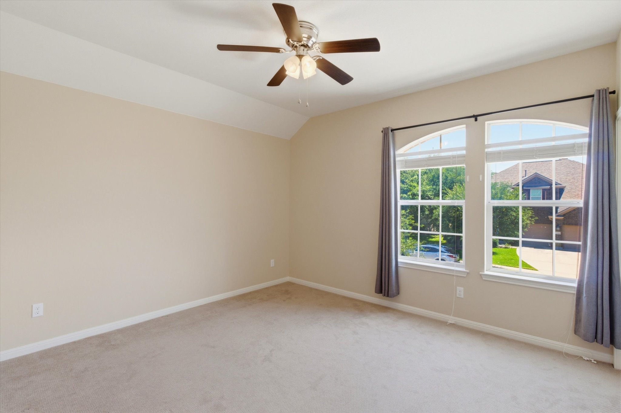 1511 Rimstone Drive Cedar Park, TX 78613 - Photo 23 of 39 A well-lit bedroom features vaulted ceilings and two arched windows overlooking lush greenery.