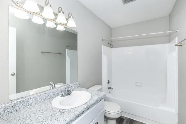 a bathroom with a granite countertop sink a toilet and shower