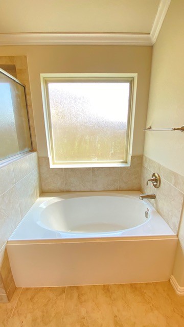 5002 Naples Grove Lane Rosharon, TX 77583 - Photo 26 of 38 Relax in this bright bathroom featuring a luxurious soaking tub and elegant tile accents, illuminated by natural light from a frosted window.