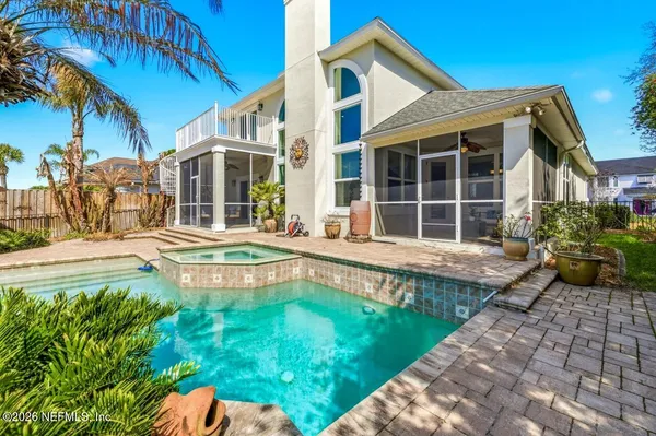 a small pool with lawn chairs under an umbrella