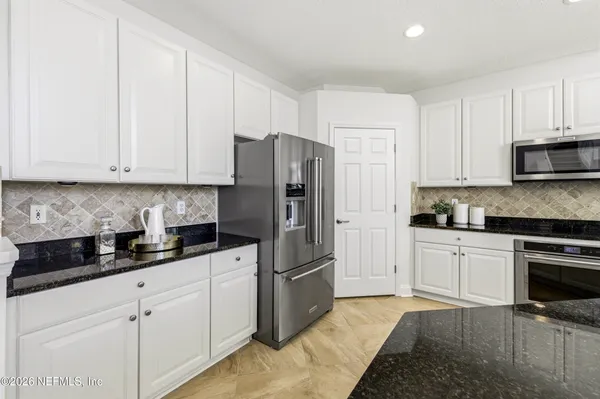 a kitchen with white cabinets and stainless steel appliances