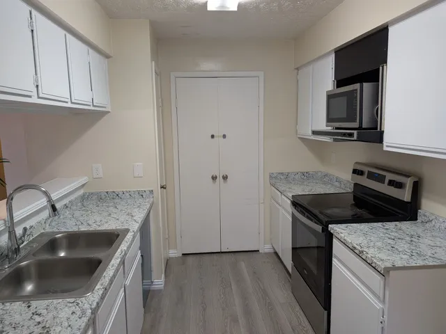 a kitchen with granite countertop a sink dishwasher stove and oven with wooden floor