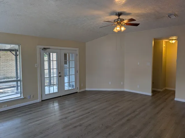 a view of an empty room with wooden floor and a window