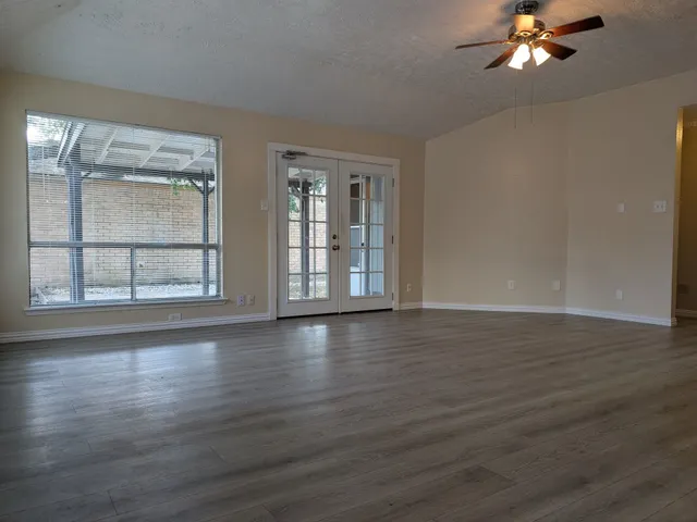 a view of an empty room with wooden floor and a window